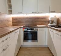 Jedinečný 3-izbový apartmán s balkónom, 71 m², Nový Ružinov - Kuchyňa v 3-izbovom byte: biele skrinky, drevená pracovná doska, spotrebiče.