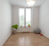 Jedinečný 3-izbový apartmán s balkónom, 71 m², Nový Ružinov - Priestranná izba v 3-izbovom byte, svetlé steny, kvetiny a fitness doplnky.