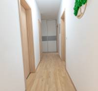 Jedinečný 3-izbový apartmán s balkónom, 71 m², Nový Ružinov - Svetlá chodba s drevenou podlahou a niekoľkými bielymi dverami v 3-izbovom byte.