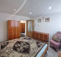 Dvojgeneračný RD, Bystré, pozemok 830 m², 3D - Spálňa v rodinnom dome s posteľou, skriňou, kreslom a dekoráciami na stenách.
