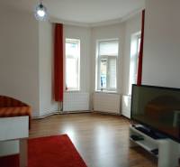 ZAUJÍMAVÝ RODINNÝ DOM, NITRA - ZOBOR - Obývacia izba s pohovkou, televízorom, stolíkom a podlahou s dreveným dekorom v rodinnom dome.