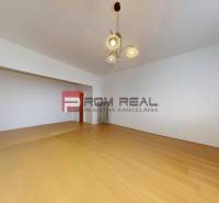Predaj 3i, 74m2 bytu s výhľadom na Draždiak, Bratislava - Priestranná miestnosť s drevenou podlahou a svietidlom v 3-izbovom byte.