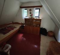 CHATA KORDÍKY - 2 poschodia, 3 izby+kuchynka, kúpelňa - 420 m2 pozemok - Podkrovná izba v chate s posteľou, skrinkou a podlahou s dreveným dekorom.