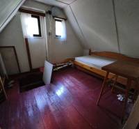 CHATA KORDÍKY - 2 poschodia, 3 izby+kuchynka, kúpelňa - 420 m2 pozemok - Izba na poschodí v chate s podlahou s dreveným dekorom, jednoduchým nábytkom a oknami.