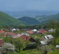 CHATA KORDÍKY - 2 poschodia, 3 izby+kuchynka, kúpelňa - 420 m2 pozemok - Pohľad na chaty v Kordíkoch pri Banskej Bystrici s malebnými kopcami v pozadí.