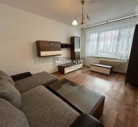 Prenájom, jednoizbový byt Rimavská Sobota, P.Hostins... - 1-izbový byt s pohovkou, dreveným nábytkom a veľkým oknom s čipkovanou záclonou.