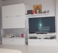 Predaj bytu 3-izbového (3+kk) s rozlohou 65 m² a terasou 10 m², Scalea - Zariadenie v 3-izbovom byte s bielymi skrinkami a televíziou na sivo maľovanej stene.