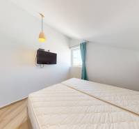 PAG/MANDRE - 2 apartmány za cenu jedného - 190m od mora - Spálňa so šikmým stropom, posteľou, televízorom a závesmi v 4-izbovom byte.