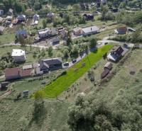 Stavebný pozemok na predaj - Raková - Letecký pohľad na obytné pozemky v obci Raková, zelené svahy a domy.