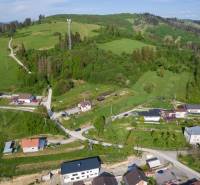 Stavebný pozemok na predaj - Raková - Letecký pohľad na pozemky pre bývanie v Rakovej, obklopené zelenými kopcami a domami.