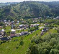 Stavebný pozemok na predaj - Raková - Letecká snímka rakovských pozemkov na bývanie obklopených zeleňou a kopcami.