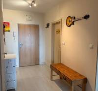 Moderný 2-izbový byt s terasou a výhľadom na mesto – Jégého alej, Nivy - Vstupná chodba v 2-izbovom byte s drevenou lavičkou a dekoratívnou gitarou na stene.