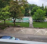 3-izb. byt, Mesačná ul., Ružinov, lodžia, 2.p./8 - Výhľad z 3-izbového bytu v Bratislave - Ružinove na Mesačnej ulici, parkovisko, stromy a ihrisko.