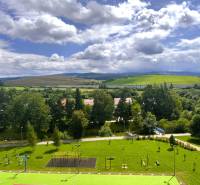 Pripravujem do ponuky!!! 2-izbový byt v Trstenej, Západ, 50m2, loggia - Pohľad z 2-izbového bytu na Západe v Tvrdošíne, s ihriskom a kopcovitou krajinou.