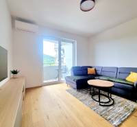 | EXKLUZÍVNE! | Krásny NOVÝ 2-izbový byt | 48m² | Čerešne - Obývačka v 2-izbovom byte s tmavým gaučom, stolíkom a balkónom.