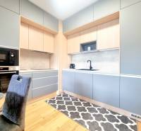 | EXKLUZÍVNE! | Krásny NOVÝ 2-izbový byt | 48m² | Čerešne - Kuchyňa v 2-izbovom byte s elegantnými sivými a drevenými skrinkami, čiernym spotrebičom a koberec.