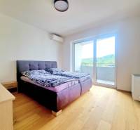 | EXKLUZÍVNE! | Krásny NOVÝ 2-izbový byt | 48m² | Čerešne - Spálňa v 2-izbovom byte s posteľou, balkónom a drevenou podlahou.