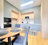 | EXKLUZÍVNE! | Krásny NOVÝ 2-izbový byt | 48m² | Čerešne - Kuchyňa s jedálenským stolom v 2-izbovom byte, vybavená spotrebičmi a drevenými skrinkami.