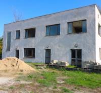 Na predaj sklady v obci Chrastince, Veľký Krtíš - Dvojposchodová budova s oknami, hlinou a zeleňou na ulici Chrastince.