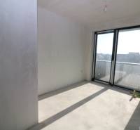 Na predaj slnečný rodinný dom v Rači - Prázdna miestnosť rodinného domu s veľkými oknami na balkón. Slnečné svetlo osvetľuje stenu.