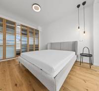EXKLUZÍVNY MEZONETOVÝ 4i byt ( 103 m2 ), NADSTAVBA, KLÍMA, LOGGIA,NIVY - Svetlá spálňa s posteľou, skriňou a závesným osvetlením. Nachádza sa v 4-izbovom byte.