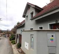 ZNÍŽENÁ cena-viacgeneračný  rodinný dom v Borinke - Rodinný dom pri ulici na Borinke s červenou strechou a okrasným levom.
