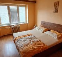 SLOVREAL - na predaj 2 izbový byt Hodruša - Hámre, 58 m2 - Spálňa v 2-izbovom byte s dreveným nábytkom, posteľou a veľkým oknom.
