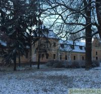 Rekonštruovaný barokový kaštieľ s kaplnkou a rozsiahlym parkom v Trávn - Zasnežený zámok v Trávnici obklopený stromami, kategória Zvláštne nehnuteľnosti.
