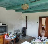 Veľký, vyše 4,5Ha slnečný pozemok s chalupou v strede, na lazoch, pri  - Interiér chaty s kachľami, starším televízorom, nábytkom a stropom modrej farby.