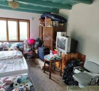 Veľký, vyše 4,5Ha slnečný pozemok s chalupou v strede, na lazoch, pri  - Interiér chaty s posteľou, televízorom, stoličkami a podlahou s dreveným dekorom.