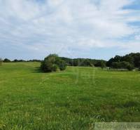 Veľký, vyše 4,5Ha slnečný pozemok s chalupou v strede, na lazoch, pri  - Rozľahlá lúka a tradičná chata v Hrušove, obklopené zeleňou a oblohou.