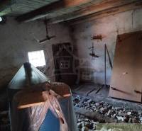 Veľký, vyše 4,5Ha slnečný pozemok s chalupou v strede, na lazoch, pri  - Interiér chaty so starými drevenými trámami, oknom a nábytkom pokrytým plachtou.