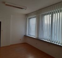 Prenájom kancelárií 21 m2 v centre Trnavy - Kancelária s podlahou s dreveným dekorom, vertikálnymi žalúziami a stropným osvetlením.