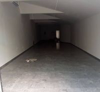 Priestor do prenájmu v centre Topoľčian - Prázdne obchodné priestory s dlažbou a veľkými presklenými dverami.
