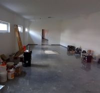 Priestor do prenájmu v centre Topoľčian - Priestranný interiér v obchodných priestoroch s množstvom náradia a materiálu na podlahe.