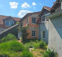 NOVÁ CENA - investičná príležitosť v obci Bíňovce - Rodinný dom v Bíňovciach na Bíňovciach s nedokončenou fasádou a bujnou vegetáciou v záhrade.