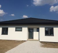 Výstavba moderného 4 izbového murovaného bungalovu - Rodinný dom v Trnave s bielou fasádou a tmavou strechou pod modrou oblohou.