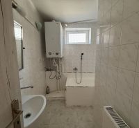 6-izbový rodinný dom s pozemkom 2218m2  | Horňany - Kúpeľňa v rodinnom dome s vaňou, bielymi obkladačkami a vykurovacím kotlom.