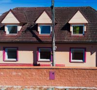 6-izbový rodinný dom s pozemkom 2218m2  | Horňany - Rodinný dom v Horňanoch s červenou strechou a omietkou v odtieni ružovej.