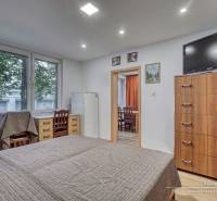 3-izbový byt v Šali na Vajanského ulici - Spálňa v 3-izbovom byte s posteľou, zásuvkami a televízorom na stene.