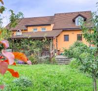 5-izbový rodinný dom s dvomi garážami v obci Špačince - Rodinný dom v Špačinciach na Špačinskej ulici s upravenou záhradou a oranžovou fasádou.