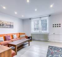 5-izbový rodinný dom s dvomi garážami v obci Špačince - Obývacia izba v rodinnom dome s oranžovou pohovkou a podlahou s dreveným dekorom.