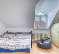 5-izbový rodinný dom s dvomi garážami v obci Špačince - Spálňa v rodinnom dome s posteľou, vreckovým kreslom a podlahou s dreveným dekorom.