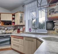 5-izbový rodinný dom s dvomi garážami v obci Špačince - Kuchyňa v rodinnom dome s kuchynskou linkou, sporákom a výhľadom cez okno.