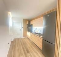 NA PRENÁJOM NOVOZREKONŠTRUOVANÝ 2-IZBOVÝ BYT, UL. ROŽŇAVSKÁ - Kuchyňa v 2-izbovom byte s podlahou s dreveným dekorom a svetlým nábytkom.