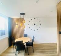 NA PRENÁJOM NOVOZREKONŠTRUOVANÝ 2-IZBOVÝ BYT, UL. ROŽŇAVSKÁ - Jedálenský kút s nástennými hodinami, drevené obklady a podlaha s dreveným dekorom.