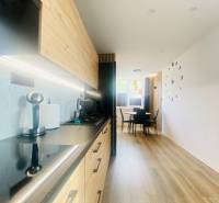 NA PRENÁJOM NOVOZREKONŠTRUOVANÝ 2-IZBOVÝ BYT, UL. ROŽŇAVSKÁ - Kuchyňa s dreveným dekorom a jedálenským kútom v 2-izbovom byte.