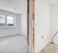 Novostavba 4-izbového rodinného domu v obci Slov.Nová Ves - Prázdna izba s veľkým oknom a neopravenými stenami v rodinnom dome.