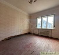 Starý dom s dušou – čaká na nový život v jednej z najkrajších ulíc Nov - Prázdna izba v rodinnom dome, so svetlým oknom a podlahou s dreveným dekorom.