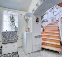 7-izbový rodinný dom s úžasným výhľadom v prestížnej lokalite Devín - Chata s dreveným schodiskom, bielym nábytkom a rastlinou; interiér s podlahou s dreveným dekorom.